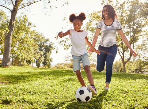A girl and her mother playing soccer